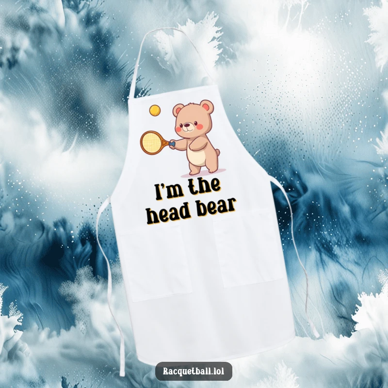 Funny apron design showing a small bear using an oversized tennis racquet as a cooking utensil, playfully swatting ingredients upwards.