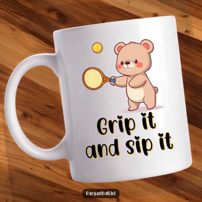 Funny mug showing a small bear struggling humorously with an oversized tennis racquet, trying to hit a bouncing ball upwards with effort.